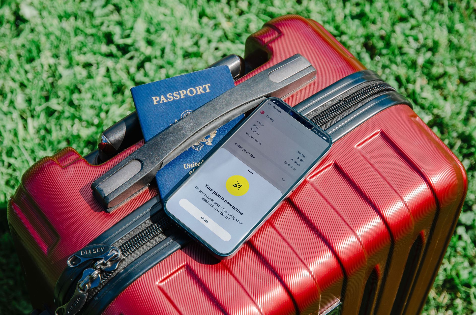 Passport and a phone with a booking on a red suitcase