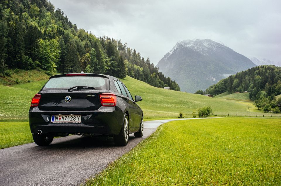 A car on a country road heading towards the mountains