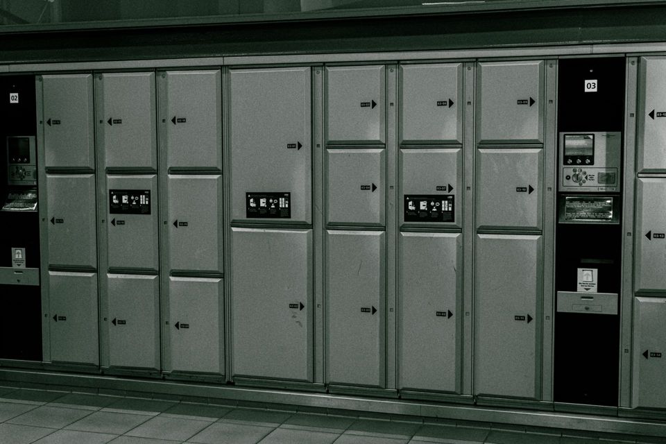 Rows of metal luggage lockers with a payment screen at a station