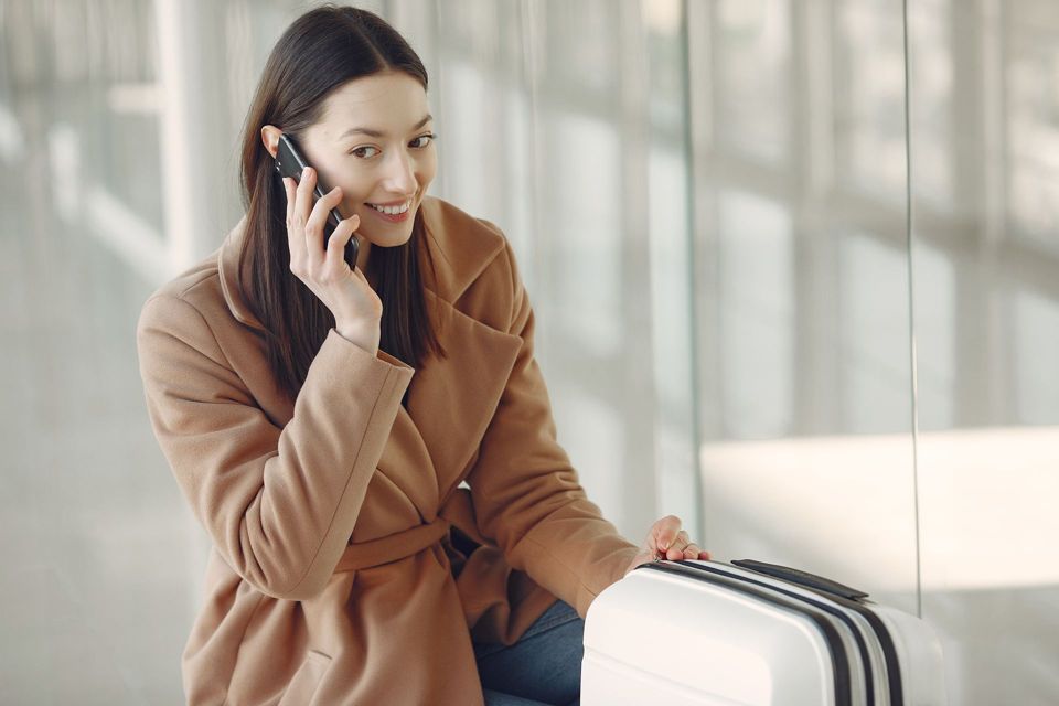 A traveller with a suitcase talking on her phone in an airport terminal